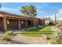 Attractive single-story home with manicured front yard, featuring desert landscaping and a walkway at 13802 N 64Th Pl, Scottsdale, AZ 85254