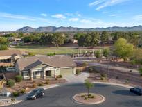 Scenic aerial view of landscaped property, neighborhood, playground and mountains in the distance at 18611 E Raven Dr, Queen Creek, AZ 85142