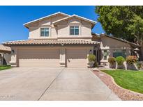 Traditional two story home with tan stucco, tile roof, three car garage, and front yard landscaping at 1920 E Belmont Dr, Tempe, AZ 85284