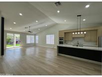Open-concept living room with a modern kitchen, expansive windows, and stylish laminate flooring throughout at 20822 N 42Nd. Ave, Glendale, AZ 85308