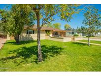 Charming home featuring a well-maintained lawn and inviting front porch, shaded by mature trees on a sunny day at 2246 E Glenrosa Ave, Phoenix, AZ 85016