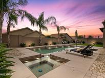 Inviting backyard pool and spa area with lounge chairs and meticulous landscaping at twilight at 4131 E Maya Way, Cave Creek, AZ 85331