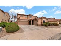 Charming two-story home with a two-car garage, complemented by manicured shrubs and blue skies at 6818 W St Catherine Ave, Laveen, AZ 85339