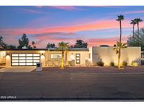 Contemporary home featuring a multi-car garage and stucco exterior complemented by desert landscaping at sunset at 9052 N 29Th St, Phoenix, AZ 85028