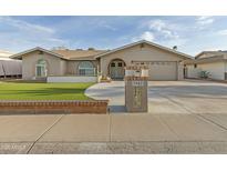Charming beige home with green turf lawn, arched windows, mailbox, and two car garage at 3907 W Sharon Ave, Phoenix, AZ 85029