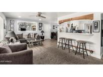 Bright living room with hardwood floors, neutral paint, ceiling fan, and breakfast bar with seating at 5422 E Des Moines St, Mesa, AZ 85205