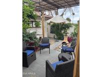 Cozy patio setting features comfortable seating, an umbrella, and a charming pergola at 12221 S Paiute St, Phoenix, AZ 85044