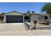 Charming single-story home with a gray garage door, xeriscaping and a well-maintained yard at 15243 N 52Nd Dr, Glendale, AZ 85306