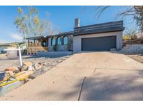 Contemporary home showcasing a two-car garage and arched windows beneath clear blue skies at 1637 E Camino Del Santo --, Phoenix, AZ 85022
