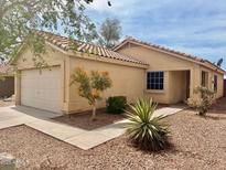 Charming single-story home features a tile roof, neutral stucco exterior, and a well-maintained front yard with desert landscaping at 168 S 223Rd Dr, Buckeye, AZ 85326
