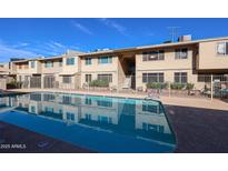 Community pool with clear blue water, surrounded by a secure fence and well-maintained building exteriors at 2605 W Rose Ln # B-202, Phoenix, AZ 85017
