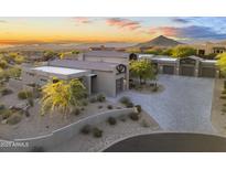 Contemporary home with desert landscaping, mountain views, and a spacious driveway at sunset at 29599 N 106Th Pl, Scottsdale, AZ 85262