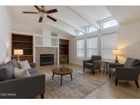Bright living room with vaulted ceilings, a cozy fireplace, and built in bookshelves at 2929 E Sequoia Dr, Phoenix, AZ 85050