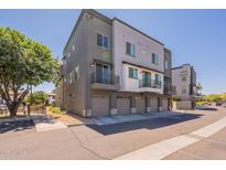 Modern townhome featuring a private balcony, gray paint scheme, and individual garages at 300 N Gila Springs Blvd # 144, Chandler, AZ 85226