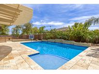 Inviting backyard pool with a waterfall feature, a basketball hoop, and a covered patio at 18543 E Purple Sage Dr, Queen Creek, AZ 85142