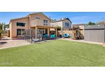 Large backyard featuring manicured artificial turf, covered patio, sitting area, and a storage shed at 4050 W Camino Del Rio --, Glendale, AZ 85310