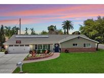 Charming single-story home with a well-manicured lawn, solar panels, and inviting front porch seating area at 601 E Winter Dr, Phoenix, AZ 85020