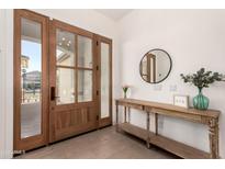 Inviting entryway featuring a wood door with glass panes, a console table, and light hardwood floors at 19162 E Mockingbird Dr, Queen Creek, AZ 85142