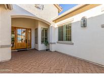 Covered front porch with brick patterned pavers, glass paneled door, and sidelight windows at 19162 E Mockingbird Dr, Queen Creek, AZ 85142