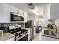 Modern kitchen with granite counters, stainless steel appliances, and a view into the living space at 12123 W Bell Rd # 339, Surprise, AZ 85378