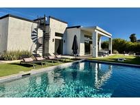 Inviting backyard oasis featuring a sparkling pool, lounge chairs, and a modern home with a spiral staircase at 5036 N Scottsdale Rd, Paradise Valley, AZ 85253