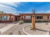 Charming single-story home featuring desert landscaping, a decorative eagle statue, and a secure gated entrance at 10855 W Buccaneer Dr, Sun City, AZ 85351