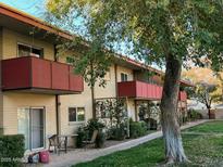 Apartment building featuring balconies, tan brick, lush landscaping and a sidewalk with outdoor seating at 355 E Thomas Rd # B207, Phoenix, AZ 85012