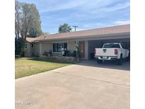 Charming single-story home featuring a lush lawn, inviting carport, and a welcoming front patio at 1257 E Dartmouth St, Mesa, AZ 85203