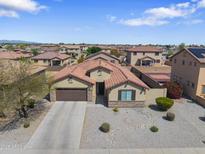 Attractive single-story home featuring a tile roof, neutral stucco, a two-car garage, and desert landscaping at 16438 W Buchanan St, Goodyear, AZ 85338