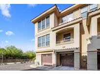 Tan townhome with private garages, covered balcony, and desert landscaping under a bright blue sky at 7275 N Scottsdale Rd # 1001, Paradise Valley, AZ 85253