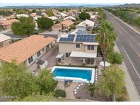 Aerial view of home with a sparkling pool, patio, and solar panels on the roof, surrounded by neighborhood and palm trees at 9509 W Tonopah Dr, Peoria, AZ 85382