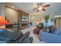 Comfortable living room features a stunning stone fireplace and modern ceiling fan at 19700 N 76Th St # 2091, Scottsdale, AZ 85255