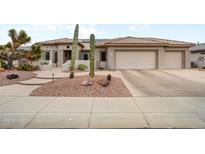 Desert landscaping accents this home featuring a tile roof and three-car garage at 20017 N Cielo Ct, Surprise, AZ 85374
