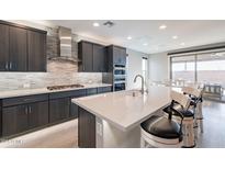 Modern kitchen featuring a large island with seating, stainless steel appliances, and stylish backsplash at 247 E Las Puertas Ln, Queen Creek, AZ 85140