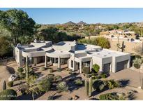 Stunning home exterior with desert landscaping, a circular driveway, and mountain views in the background at 9726 E Hidden Green Dr, Scottsdale, AZ 85262