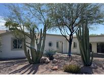 Charming single-story home with desert landscaping featuring cacti, trees, and gravel, enhancing curb appeal at 3907 E Marilyn Rd, Phoenix, AZ 85032