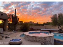 Backyard pool and spa with desert landscaping set against a vibrant sunset sky at 8625 E Camino Vivaz --, Scottsdale, AZ 85255