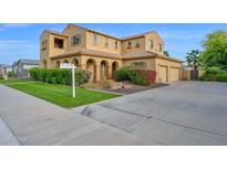 Well-maintained home with a manicured lawn, mature landscaping, and a welcoming driveway leading to a spacious garage at 21525 E Camacho Rd, Queen Creek, AZ 85142