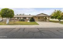 Charming single-story home with a well-manicured lawn and covered carport at 10927 W Peoria Ave, Sun City, AZ 85351