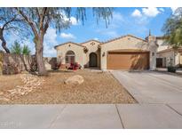 Tan home showcasing a well-manicured yard and front entrance on a sunny day with blue skies and a two car garage at 5320 W Fawn Dr, Laveen, AZ 85339