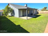 View of backyard featuring well-maintained green grass and covered patio at 8512 W Tuckey Ln, Glendale, AZ 85305