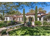 Expansive lawn and well-manicured garden lead to the stately home with stone accents and mature trees at 8601 N 59Th Pl, Paradise Valley, AZ 85253
