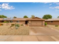 Single-story home featuring a desert rock yard, covered porch, and a two-car garage at 18211 N Conestoga Dr, Sun City, AZ 85373