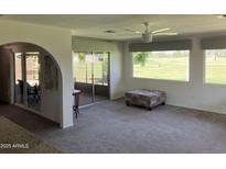 Bright living room offering golf course views from large windows and sliding doors to the enclosed patio at 18211 N Conestoga Dr, Sun City, AZ 85373