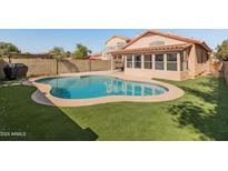 Sparkling private pool surrounded by artificial grass and block fence, creating a serene outdoor oasis at 19412 N 77Th Ave, Glendale, AZ 85308