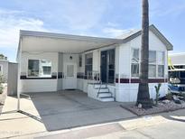 Charming manufactured home featuring a covered carport and well-maintained landscaping at 457 S Jaspar Dr, Apache Junction, AZ 85119