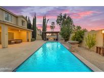 Inviting backyard pool with a stone water feature and a covered patio area with a fire pit under a vibrant sky at 4630 E Hazeltine Way, Chandler, AZ 85249
