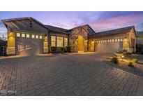 Stunning home featuring a stone archway, three-car garage, and brick driveway under a picturesque twilight sky at 10778 N 137Th St, Scottsdale, AZ 85259