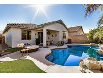 Backyard pool with a covered patio, lounge seating, and palm trees, perfect for outdoor relaxation at 17704 W Tasha Dr, Surprise, AZ 85388