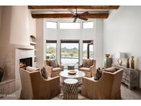 Bright living room with fireplace, wood beam ceiling, and views of the outdoor pool and desert landscape at 8400 E Dixileta Dr # 153, Scottsdale, AZ 85266